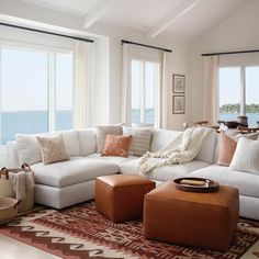 a living room filled with lots of furniture and large windows overlooking the water in front of them