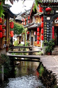 a river running through a small town with lots of red lanterns hanging from the buildings