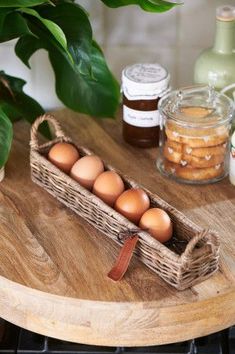 a basket filled with eggs sitting on top of a wooden table next to some jars