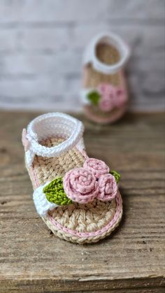 crocheted baby sandals with pink flowers on the bottom and green leaves at the top