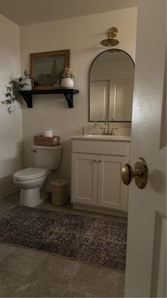 a bathroom with a toilet, sink and mirror on the wall next to a rug