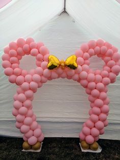 a pink balloon arch with a yellow butterfly on top