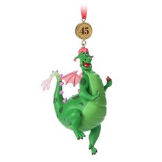 a green and pink dragon ornament hanging from a red ribbon on a white background