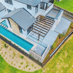 an aerial view of a house with a swimming pool in the foreground and green grass on the other side