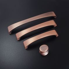 three pieces of copper metal on a black surface with a round object in the middle