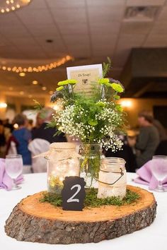 the table is set up with mason jars and greenery for centerpieces, including baby's breath