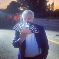 an older man holding a fan with the word luck out on it in front of him