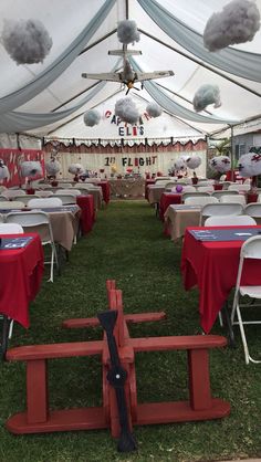 an outdoor tent with tables and chairs covered in red tablecloths