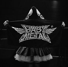 a woman holding up a black and white shirt with the words baby metal on it