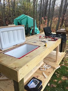 an outdoor table with tools on it next to a stove top oven and picnic table