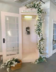 the phone booth is decorated with white flowers and greenery for an event or wedding