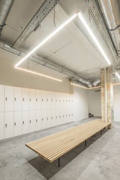 an empty room with lockers and benches in the center, surrounded by concrete flooring