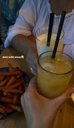 a person holding up a drink in front of a plate with fries on the side