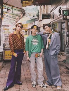 three young men standing next to each other on a brick sidewalk in front of stores