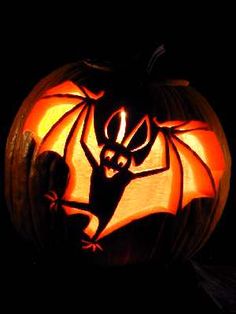 a carved pumpkin with an image of a bat on it's face in the dark