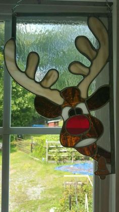 a stained glass reindeer head hanging from a window