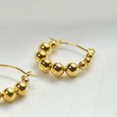 Beaded Hoop Earrings14K Gold Plated Stainless SteelOur Beaded Hoops are the perfect marriage of elegance and charm and will make a delightful addition to any jewelry collection. This lightweight accessory is minimalist in make, yet timeless in style. The unique pair is made with 14K Gold Plated Stainless Steel allowing its color to remain over time.All of our products are lightweight and made with hypoallergenic materials to allow for comfortable, all day wear.The Beaded Hoop Earrings are the pe Yellow Gold Beaded Hoop Earrings For Gift, Gold Hoop Earrings With Round Beads, Gold 14k Gold-filled Hoop Earrings With Round Beads, Elegant Hoop Earrings With Gold Beads, Dainty Gold Hoop Earrings With Round Beads, Gold Round Beads Earrings For Everyday, Everyday Gold Round Bead Earrings, Everyday Gold Beaded Round Earrings, Elegant Everyday Hoop Earrings With Round Beads