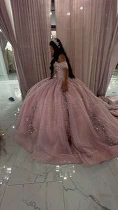 a woman in a pink ball gown is sitting on the floor with her hands behind her back