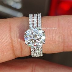 a woman's hand with a diamond ring and two bands on her finger,