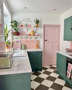 a kitchen with pink and green cabinets, checkered flooring and white counter tops