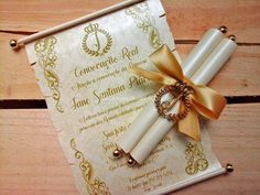 two rolled up papers tied together with gold ribbon on top of each other next to a golden bow