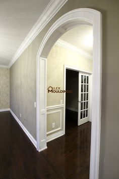 an empty room with wood flooring and white trim on the walls, leading to a doorway