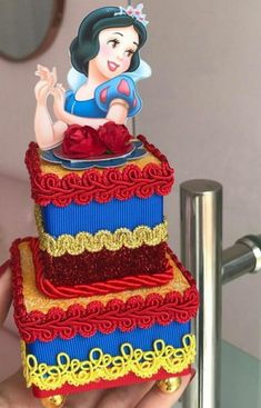 a woman holding up a cake made to look like snow white