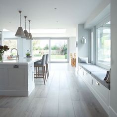 a large kitchen with white cabinets and wooden flooring, along with an island in the middle