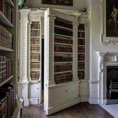 the room has many bookshelves in it, and there are paintings on the wall