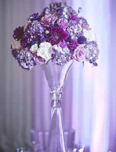 a vase filled with lots of purple and white flowers