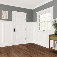 an empty room with wood floors and white doors on either side of the door is a plant in a vase