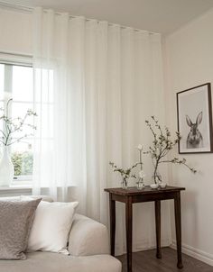 a living room with a white couch and table in front of a window filled with flowers