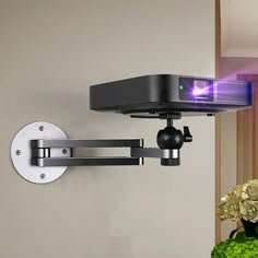 a wall mounted projector with a camera attached to it's arm and the light on