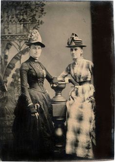 an old photo of two women standing next to each other with hats on their heads