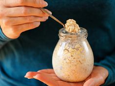 a person holding a spoon in a jar filled with oatmeal