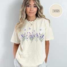 Lavender Wildflowers Comfort Colors® T-Shirt, Summer Wildflowers Tee Shirt, Lavender Shirt, Summer Wildflowers Shirt Gift, Lavender Gift Tee. Orders are processed within 24 hours and shipped out within 2 to 5 business days. What you receive: Comfort Colors® Adult Unisex Crewneck T-shirt Color Choices: Ivory White Pepper Orchid Sizes: Unisex adult sizing use size chart as a guide. These shirts are fitted and run true to size. If you prefer a loose fit go one size larger. If you want an oversized Summer Lavender Tops With Graphic Print, Lavender Graphic Print Tops For Summer, Lavender Tops With Graphic Print For Summer, Lavender Short Sleeve T-shirt For Summer, Lavender Relaxed Fit T-shirt For Spring, Lavender Crew Neck T-shirt For Summer, Lavender Floral Print Cotton Top, Lavender Cotton Tops With Floral Print, Lavender Graphic Cotton Tee