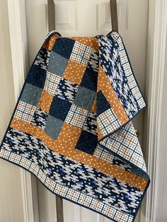 two quilts are hanging on a door hanger, one is blue and the other is orange