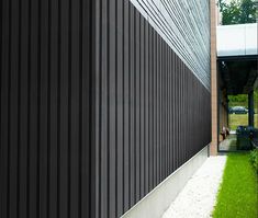 the side of a building with grass and trees