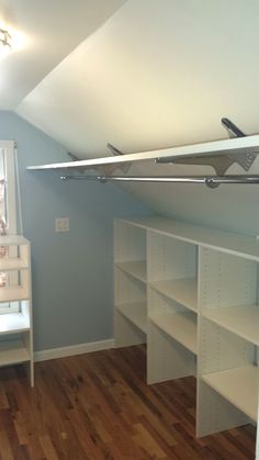 an empty room with white shelves and wooden floors