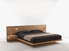 a bed that is made up with a night stand on one side and a lamp on the other