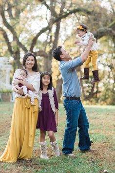 a family posing for a photo in the park with their toddler daughter and dad