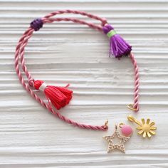 a bracelet with tassels and charms hanging from it on a white wooden surface