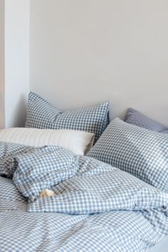 an unmade bed with blue gingham comforter and pillows on the side