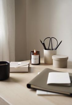 a desk with a candle, pen holder and other items on top of the table