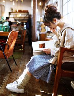 a woman sitting at a table with a book in front of her and looking down