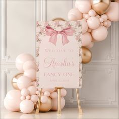 a welcome sign and balloons in front of a white wall with pink flowers on it