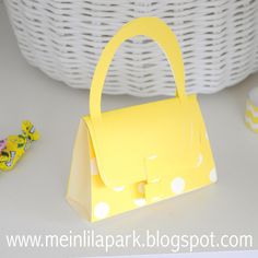 a small yellow purse sitting on top of a white table next to flowers and candy