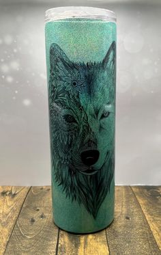 a green colored tumbler with a wolf on it's side and an intricate design