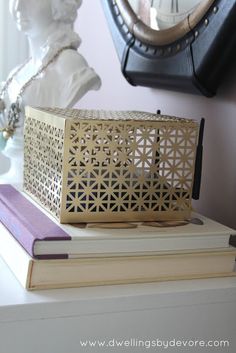 a wooden box sitting on top of two books in front of a clock and busturine