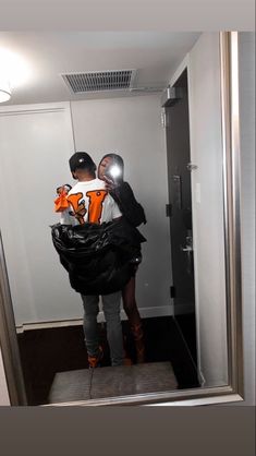 two people are standing in the bathroom and one is holding a bag